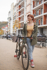 Obraz na płótnie Canvas Vertical full length shot of a young woman walking city streets with her bicycle