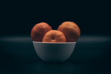 mandarinas en una bol blanco sobre fondo negro. 