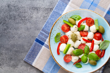 Delicious caprese salad with ripe cherry tomatoes and mini mozzarella cheese balls with fresh basil leaves.