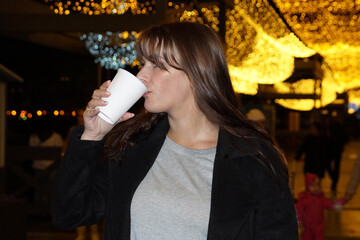 the girl drinks coffee on the street in the evening