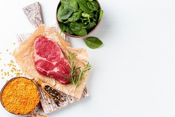 Fresh raw rib-eye steak on wooden cutting board.