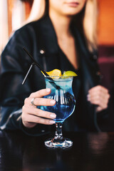 Cocktail blue lagoon in the hands of a girl close up