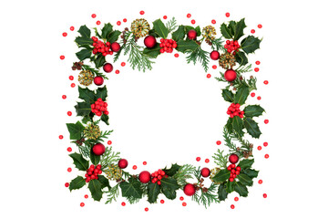 Christmas square wreath of winter holly, red bauble decorations, cedar leaves, ivy florets & loose red berries on white. Background border & festive scene for a greeting card. 