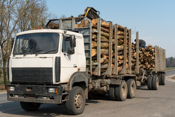 Transportation of wood on a truck with a trailer on the highway. Industrial truck for transporting...