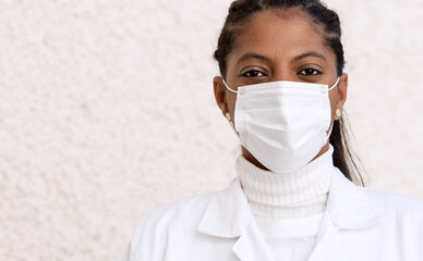 Portrait of an African-American doctor in a white coat and mask. Copy space