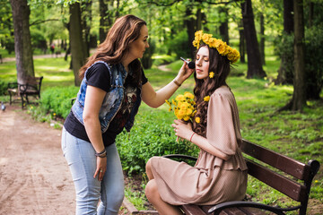 make up artist doing professional make up of young woman. Make-up artist work on her friend.Real people.