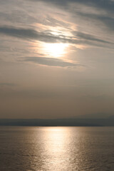 Sunset at Garda lake, Italy. Sun behind clouds with reflections. 