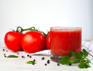 Glass of fresh tomato juice, ripe tomatoes and salt on a white background. Close-up.