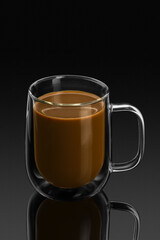 double wall glass mug with coffee on a black background with reflection