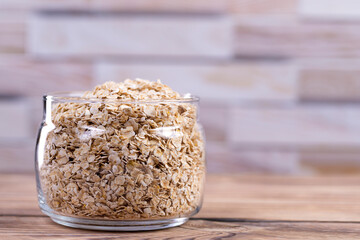 Oatmeal in a glass jar on a wooden table with place for text. Side view. Raw oatmeal