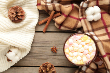 Cup of hot chocolate and marshmallows with cinnamon sticks on vintage wooden background.