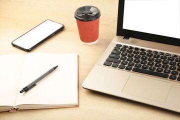 Laptop computer white blank screen and smartphone on wood table. View from above.