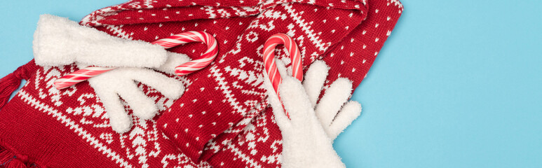 top view of winter accessories and candy canes on blue background, 