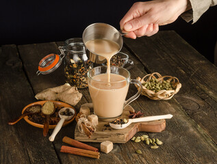 Woman pours masala tea with spices, a warming drink