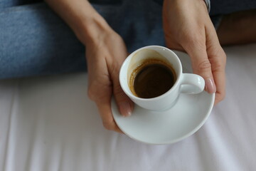 a cup of esperesso coffee in the hands of a girl