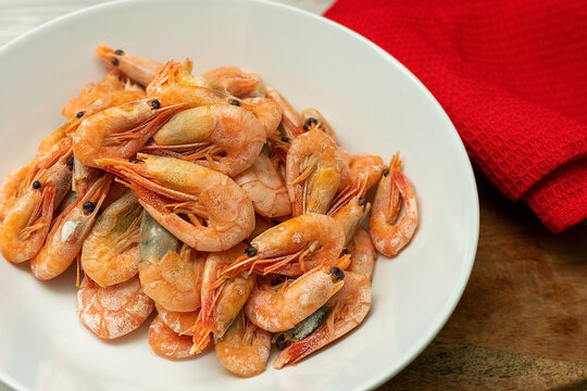 Steamed shrimp on a white plate with seafood sauce in a small bowl.