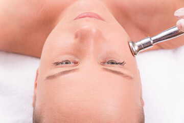 The cosmetologist makes the procedure Microdermabrasion of the facial skin