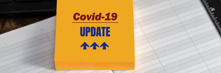 Naklejka na ściany i meble COVID-19 UPDATE text on yellow sticker on desktop background, banner format.