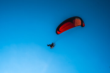 Paraglider in the air, beautiful blue sky in the background.
