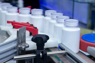 white medicine plastic bottle on production line of conveyor at filling machine in medical factory....