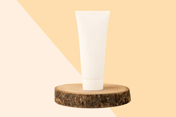 Blank cosmetics tube stand on the top of wood cut.Beautiful pastel beige isometric background.Organic copcept.