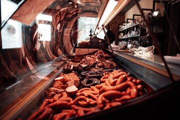 A counter full filled with row of quality raw and smoked in modern and styled butcher's shop.