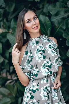 Portrait Of Happy Young Pretty Woman With Dark Brown Hair On Summer Blooming Plants Green Park Background