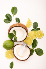 Top view of lime, coconut halves, bottle of lotion and rose leaves on white, stock image