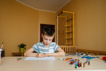 A school-age boy does homework at home. Training at school