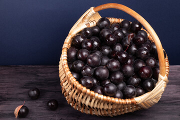 wicker basket with plums on a dark wooden table