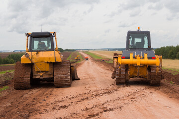 Obraz premium Bulldozer during road construction. Construction machinery. Earth moving by a bulldozer in the construction of a road. Excavator on a construction site of a road