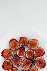Ripe and sweet figs cut and arranged in a plate on a white background with free space. Fruits and vegetarianism