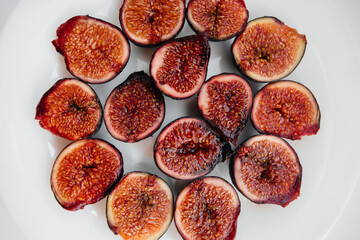 Fototapeta na wymiar Ripe and sweet figs cut and arranged in a plate on a white background with free space. Fruits and vegetarianism