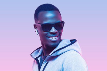 Portrait of handsome young african american man listening music with earphones, wearing sunglasses