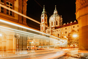 Fototapeta na wymiar Night view of St. Nicolas Church, Prague, Czech republic. Long exposure city lights.Motion speed scene.Traffic trails in town.City street at night.Transportation travel background.Urban development.