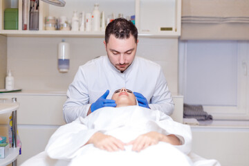 Doctor makes a markup on the face of a beautiful female before the comet procedure for correcting...