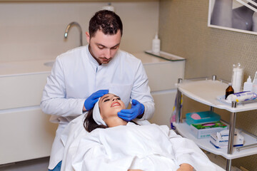 Doctor makes a markup on the face of a beautiful female before the comet procedure for correcting...