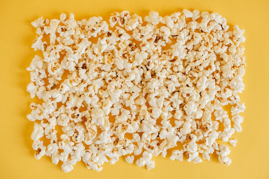 Popcorn on a yellow background as a background image. Top view. Copy, empty space for text