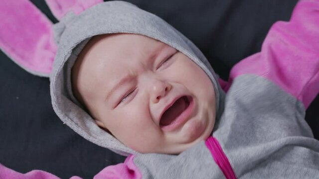 A Baby Lies on the Bed and Cries. Child is Upset and Crying.