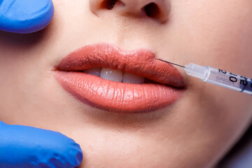 young woman gets injection of botox in her lips. Woman in beauty salon. plastic surgery clinic.