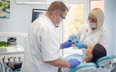 Obraz premium Doctor dentist treats teeth of a beautiful young girl patient. The girl on reception at the dentist. Doctor dentist treats tooth