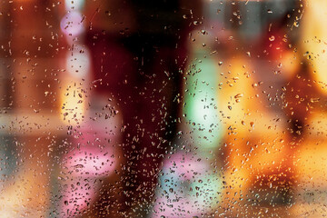 Wet window with rain drops, blurred street bokeh. Abstract blurred colorful background. Concept of weather, seasons, city at night