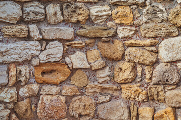Ancient stone wall made of stones of different colors.