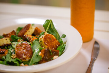Plato de ensalada fresca con lechuga y semillas emplatado con juga de naranja