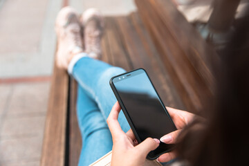 woman holding phone sitting in bench
