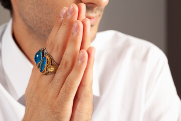 Blue silver rings and accessories on male finger with blue tie in white shirt.