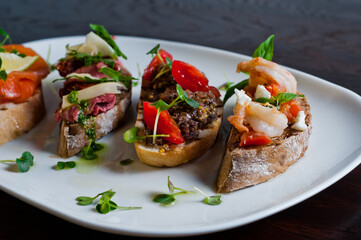 Bruschetta with herring,pate and meat on black wooden background. Close-up.