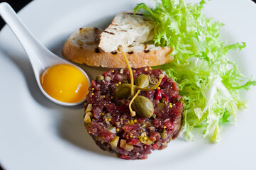 Beef carpaccio on black plate with mustard and parmesan