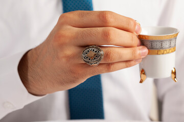 Silver ring on finger of man in white shirt and blue tie.