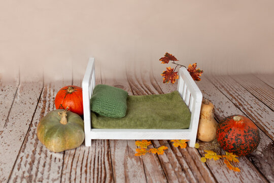 the wooden bed is decorated with autumn leaves and pumpkins. photo zone for a photo session of newborns. the bed is made of solid wood. backdrop for photography newborn